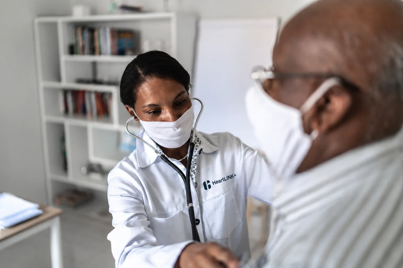A clinician listens to a patient’s chest with a stethoscope during a consultation.